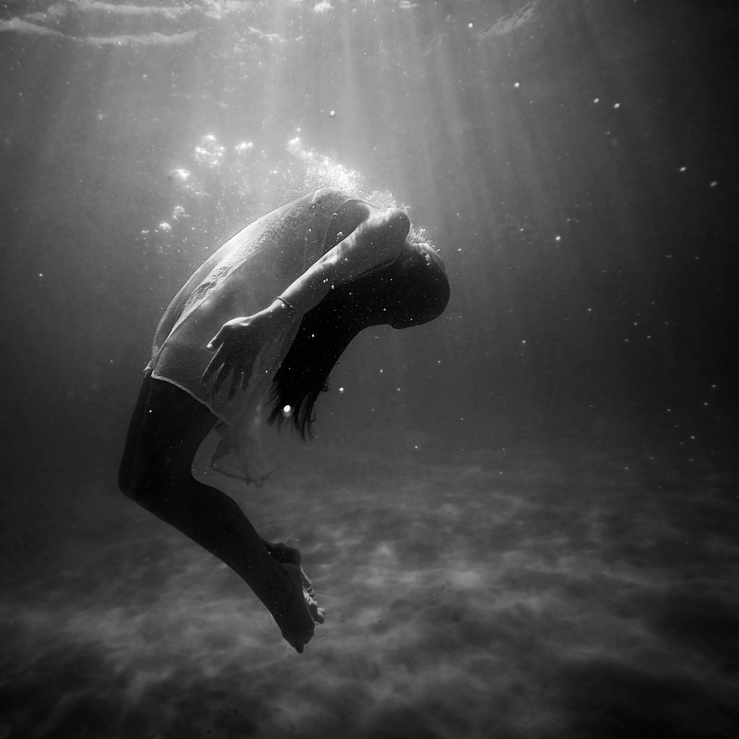 Person submerged underwater reaching upward